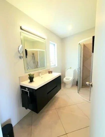 A bathroom with a long vanity, a mirror and a walk-in shower