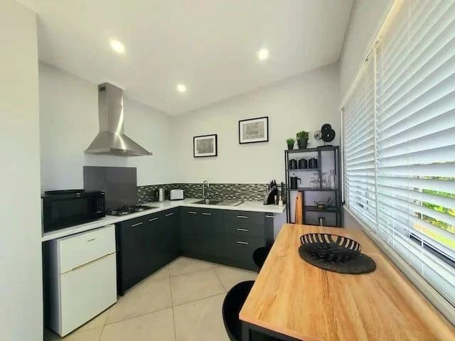 The studio kitchen with a timber table and a window onto the garden