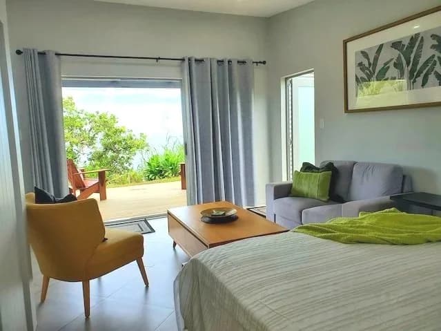 The studio's lounge chair, sofa and bed, with glass doors open to the deck